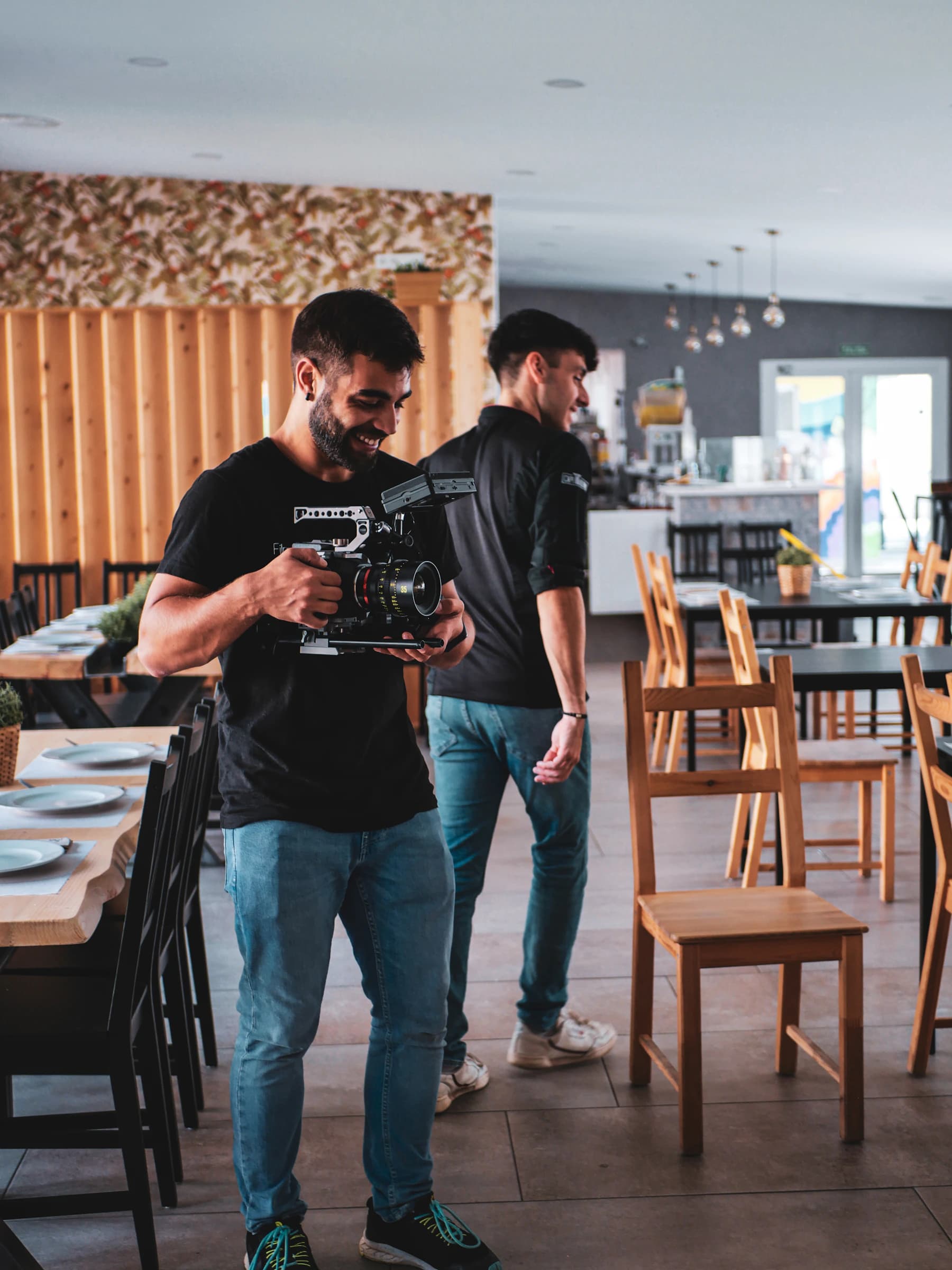 Zwei Kameraleute filmen in einem Restaurant, einer mit Kinokamera in der Hand.